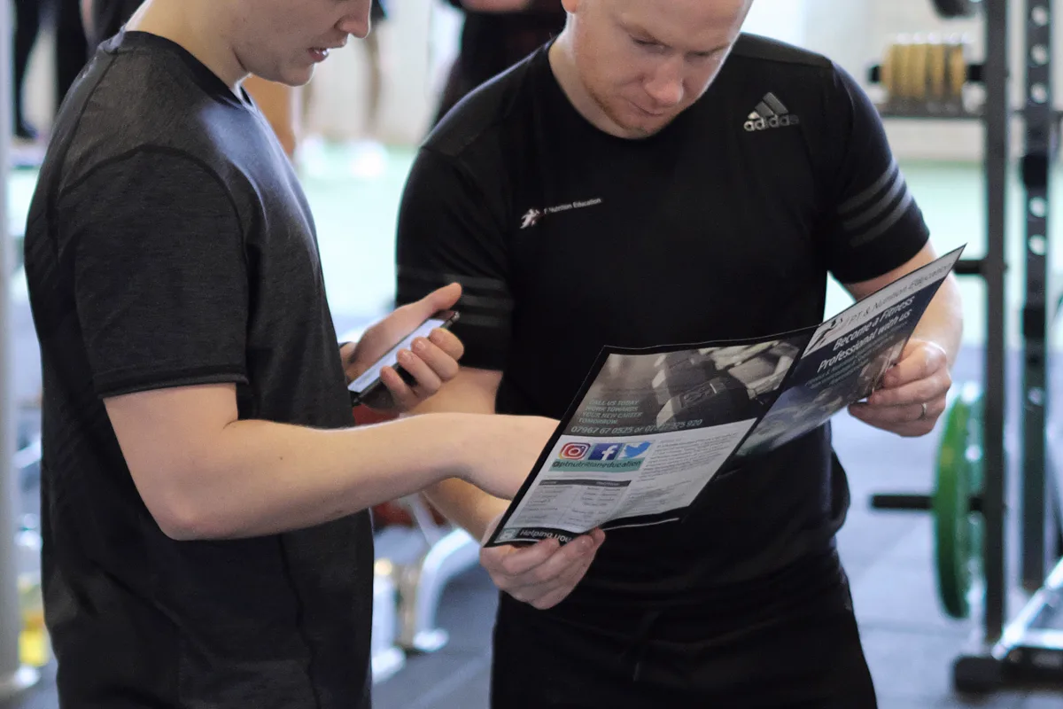 A tutor talking a learner through a session on the gym floor