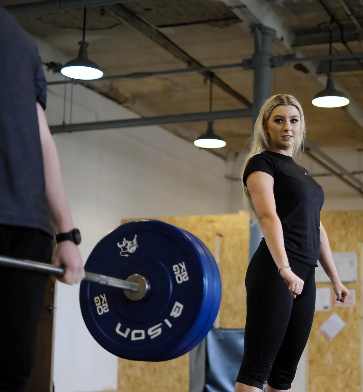 A learner setting up a deadlift while a tutor coaches