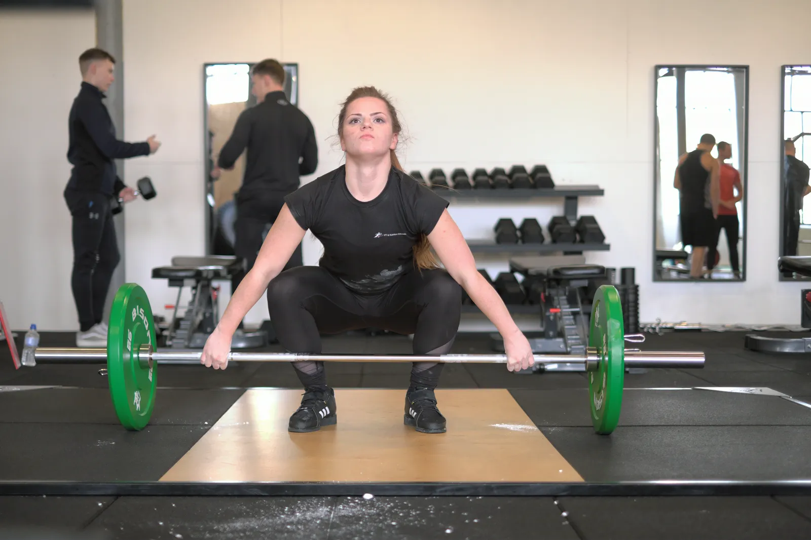 An athlete preparing a snatch while a coach watches