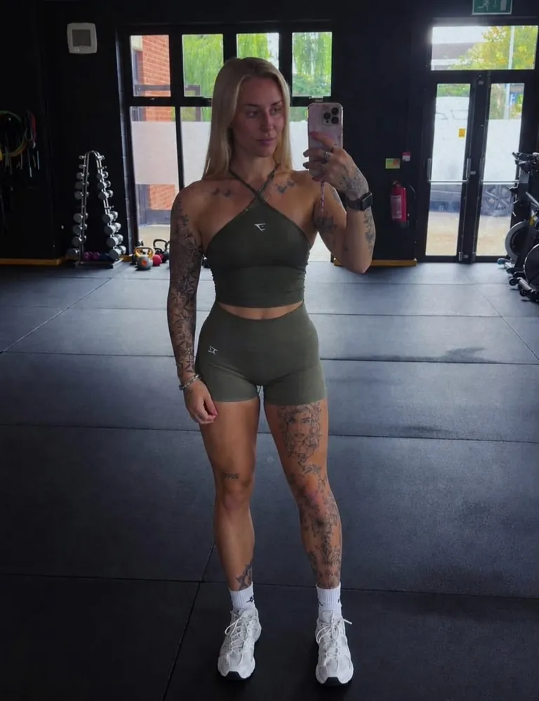 Millie Sansom in a gym, taking a mirror photo