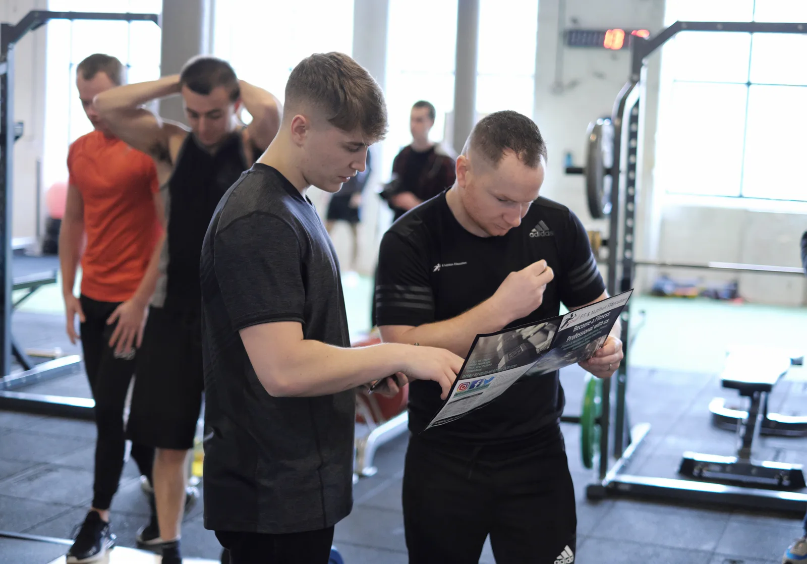 A tutor and a learner going through course material together on the gym floor